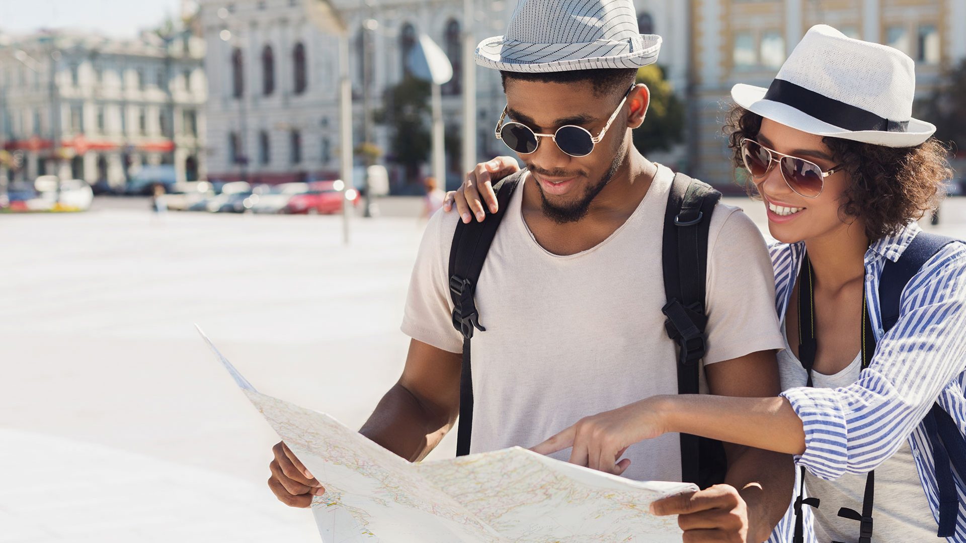 Couple with nice sunglasses looking at a map in a city